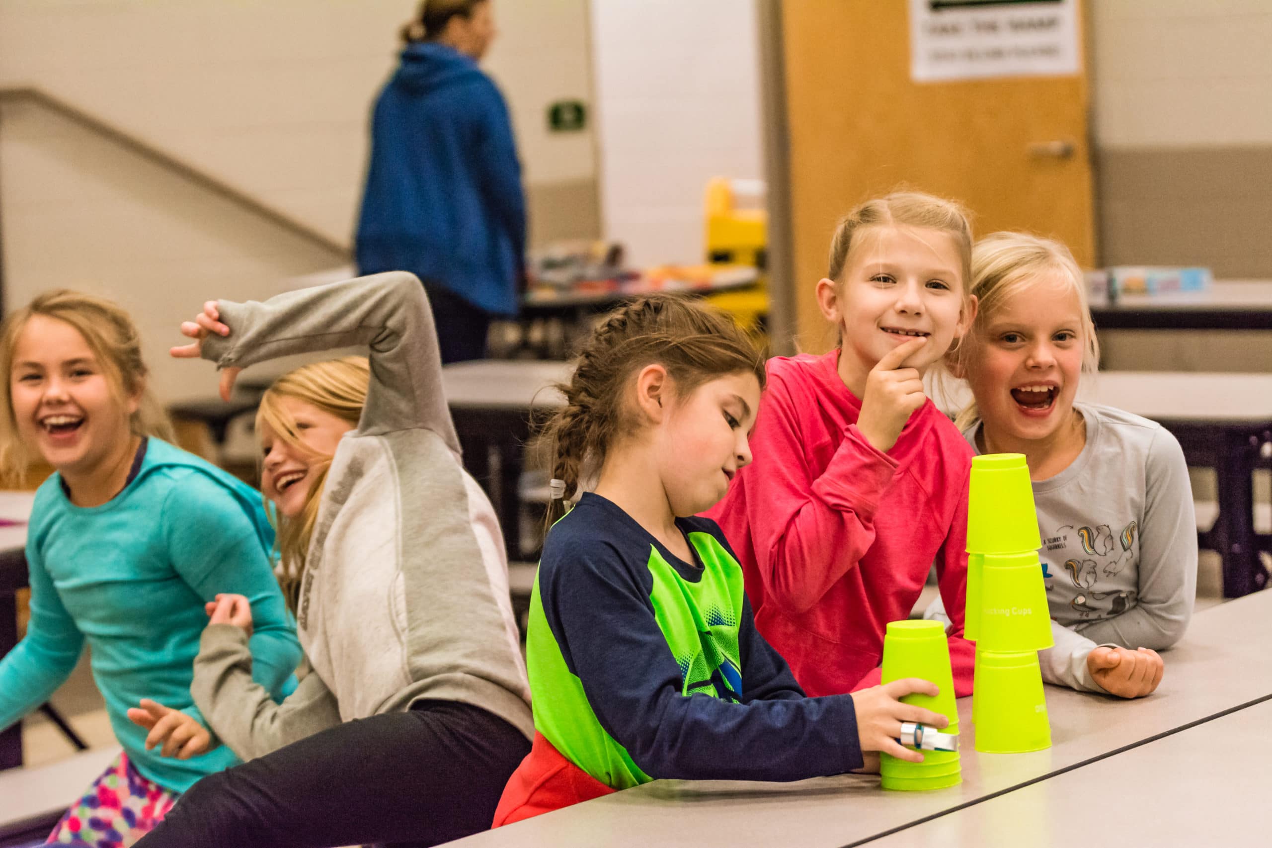 alt=Photo of young FLYERS students smiling while practicing cup stacking