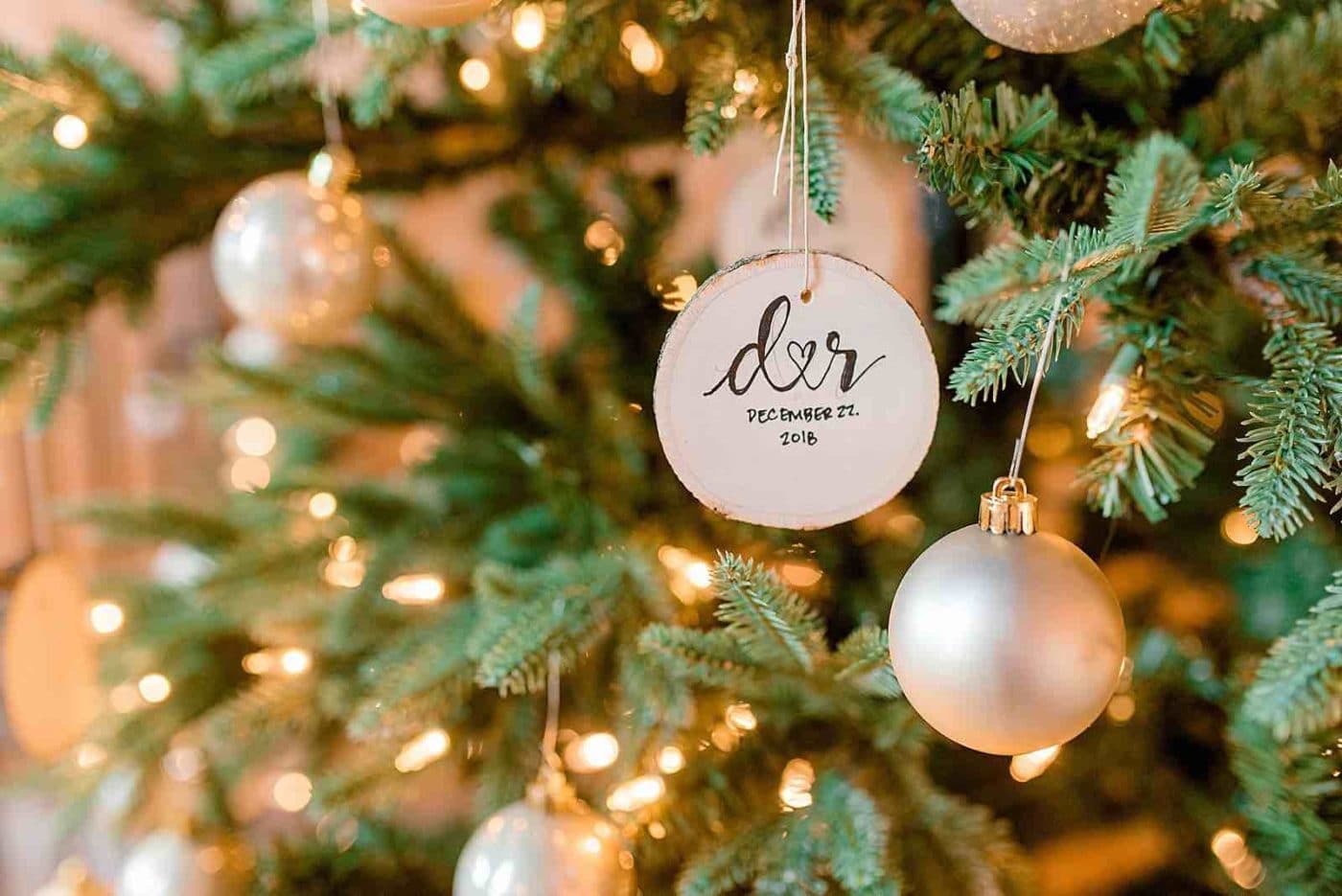 alt=Photo of a tree bark ornament hanging on a Christmas tree with the letters D and R burned onto it