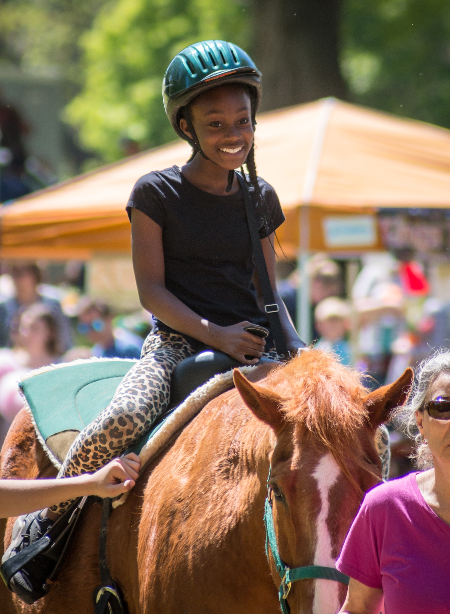 alt=Photo of young girl smiling while riding a horse at Anne Springs Close Greenway