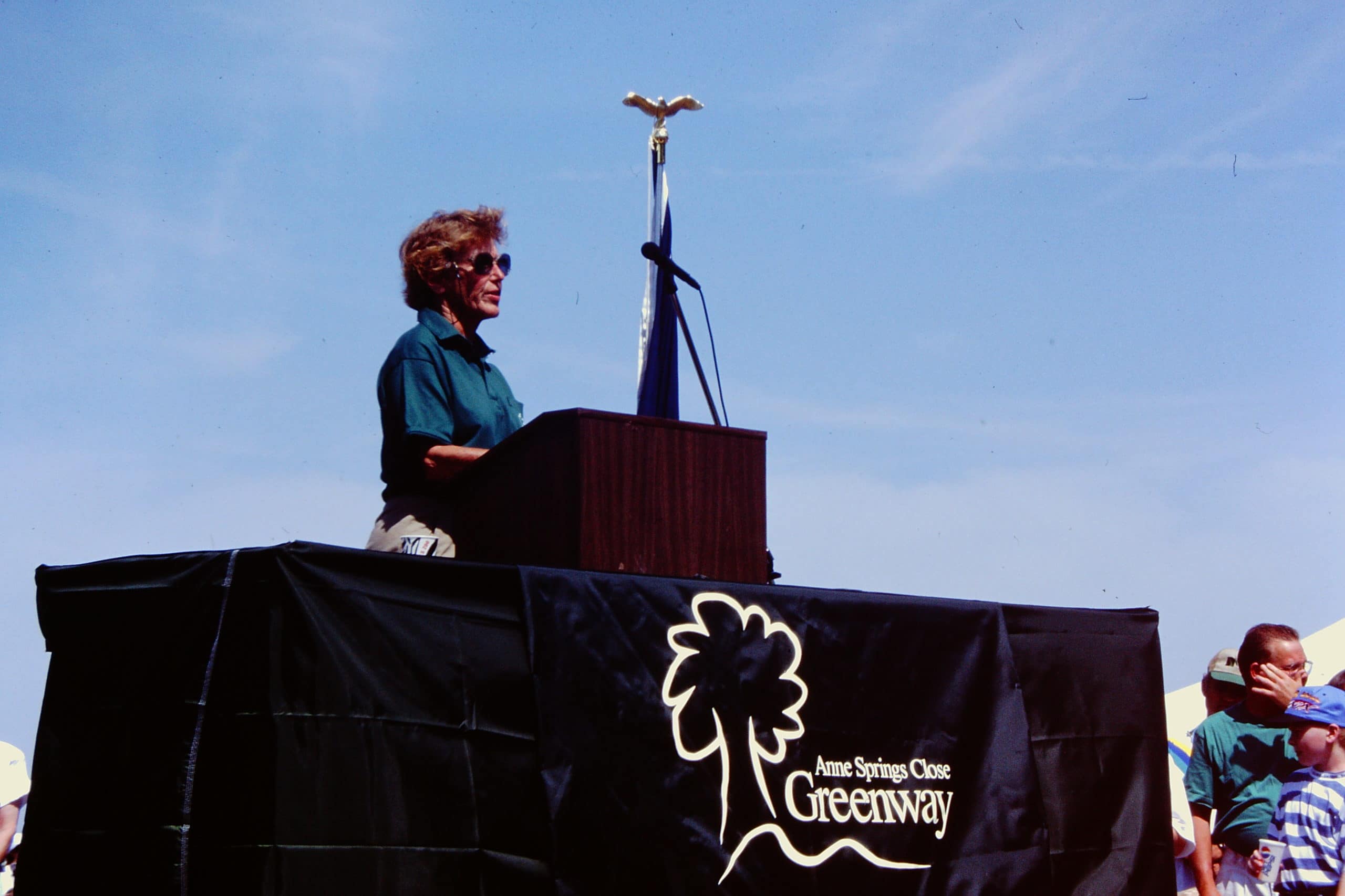 alt=Photo of Ms. Anne Springs Close speaking at the podium of the Anne Springs Close Greenway