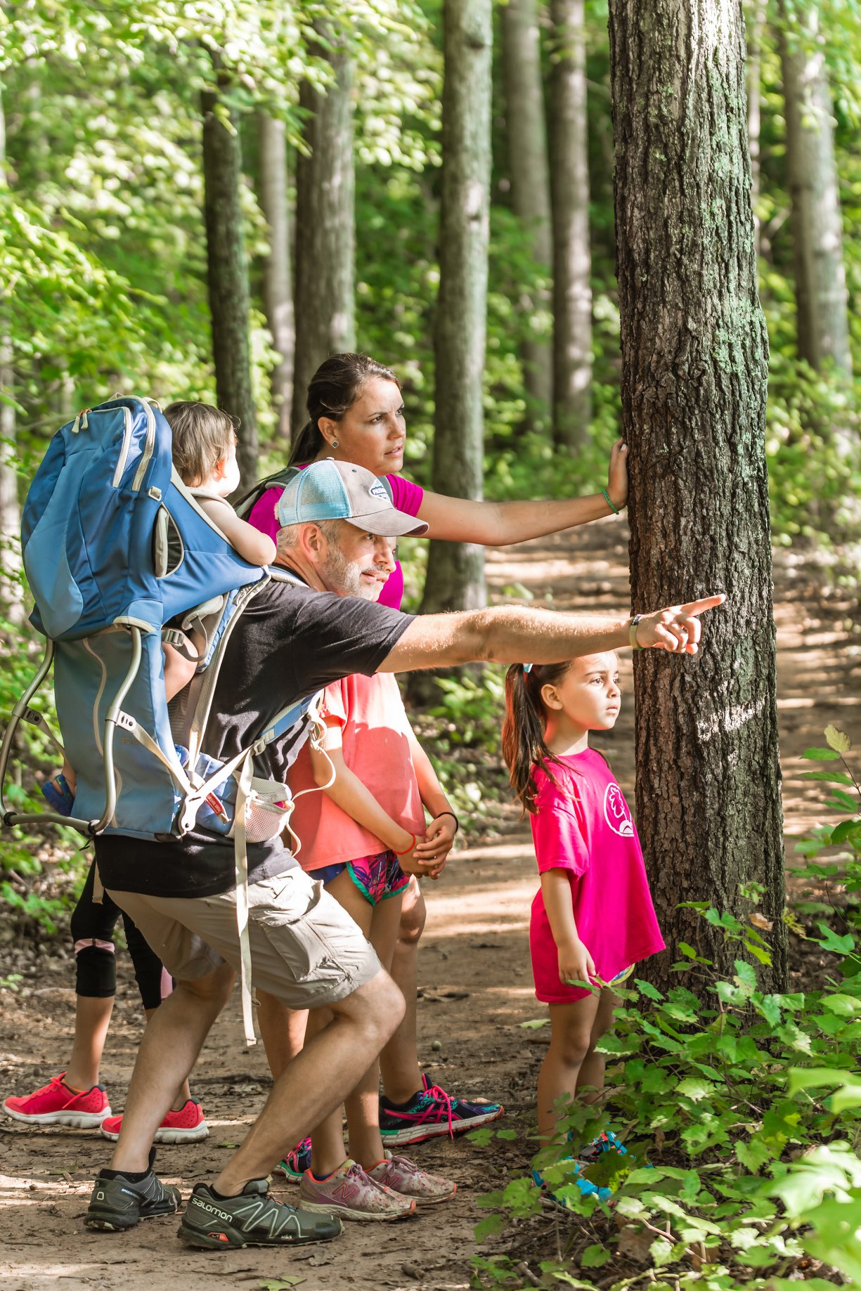 Photo of father and mother pointing out something to their children in the woods of the Anne Springs Close Greenway