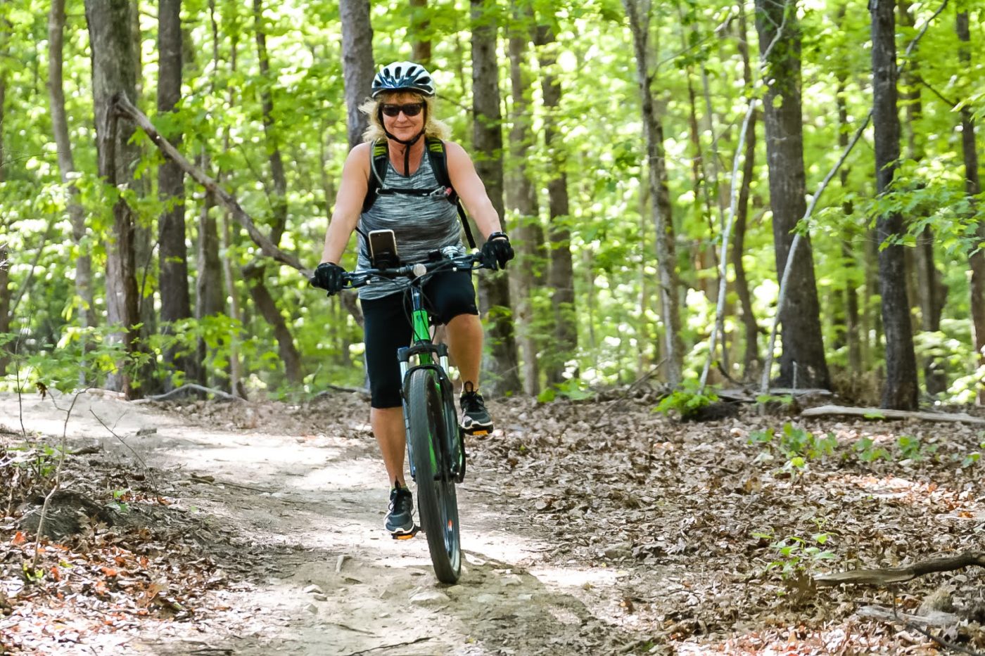 alt=Photo of woman biking along a trail at the Anne Springs Close Greenway