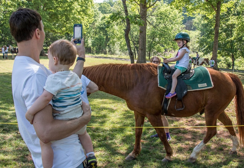 alt=Man taking photo of girl on horse