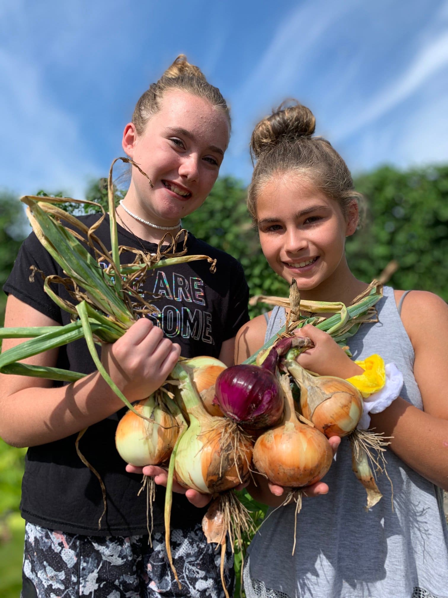 Photo of 2 girls holding vegetables harvested from the Community Garden at the Anne Springs Close Greenway