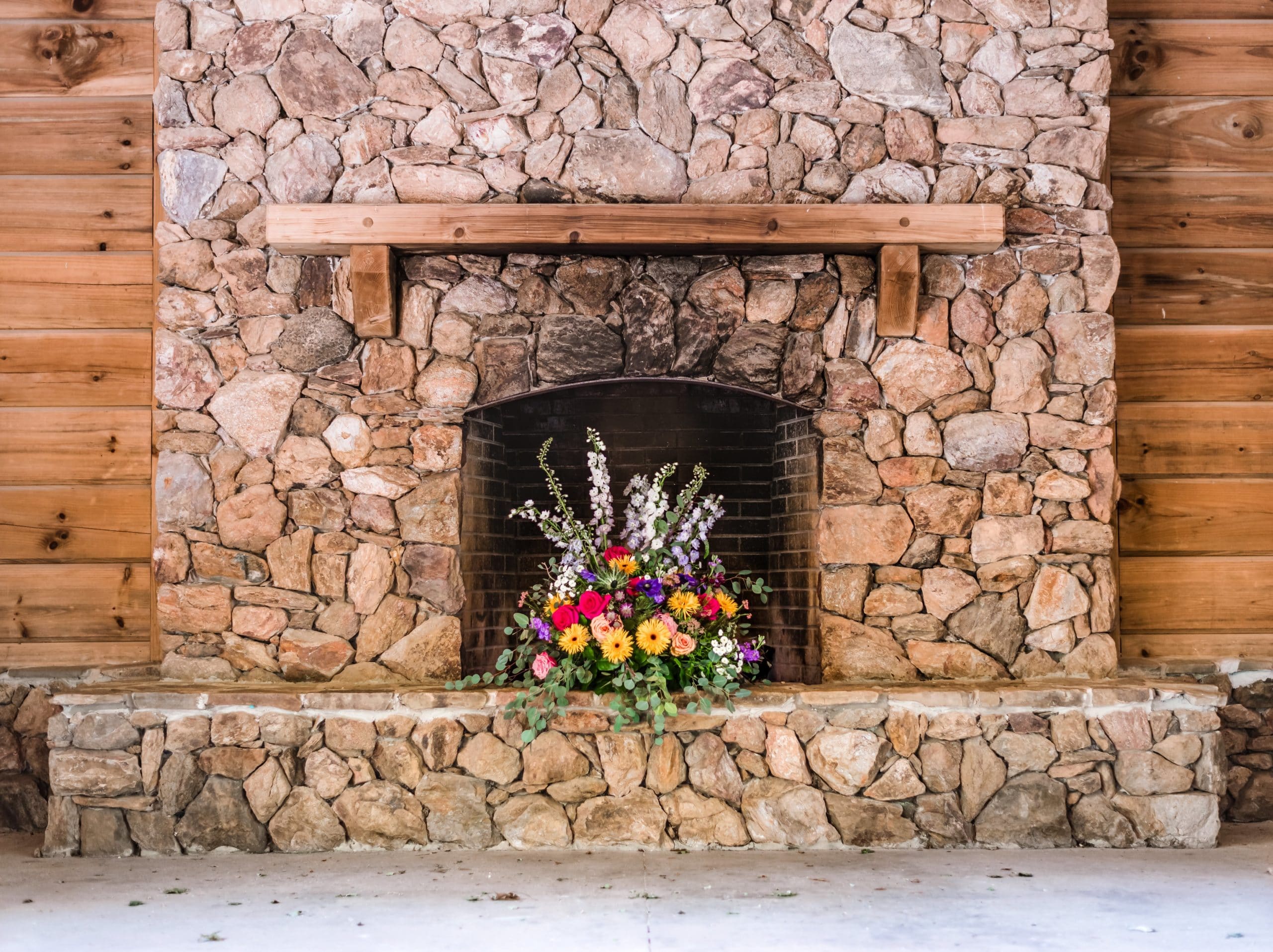 alt=Photo of fireplace with flower bouquet sitting on the mantle