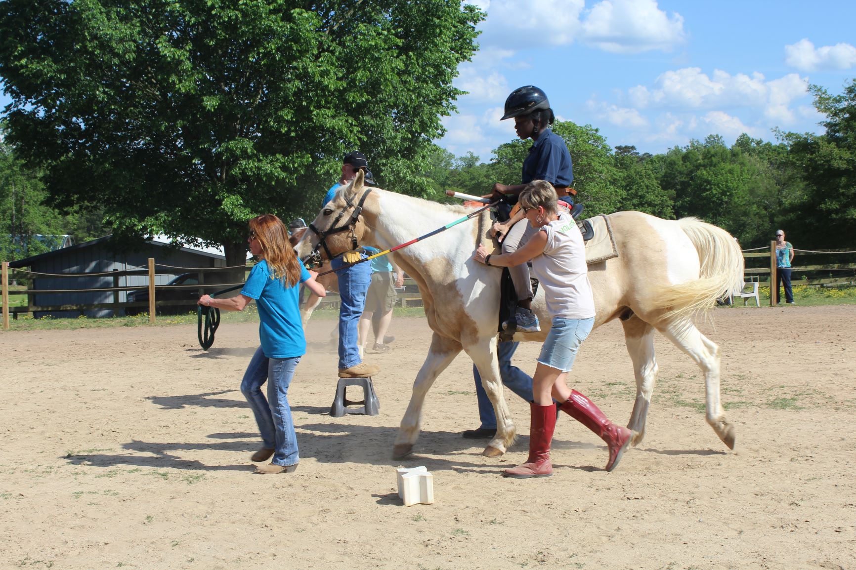 Photo of young child riding a horse while 2 handlers guide them