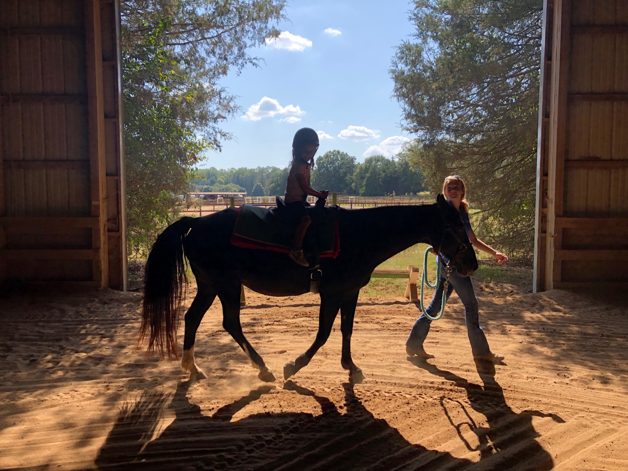 Photo of young child riding a horse around the barn of the Anne Springs Close Greenway