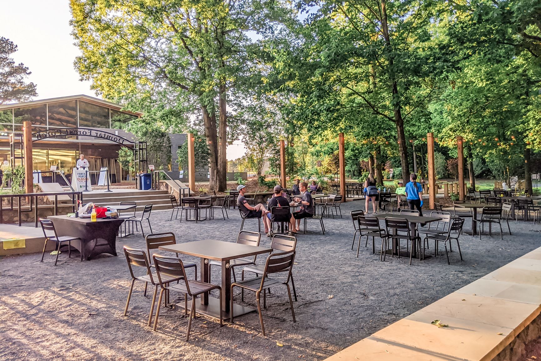 alt=Photo of guests sitting at tables of the Domtar Forest Porch at the Anne Springs Close Greenway