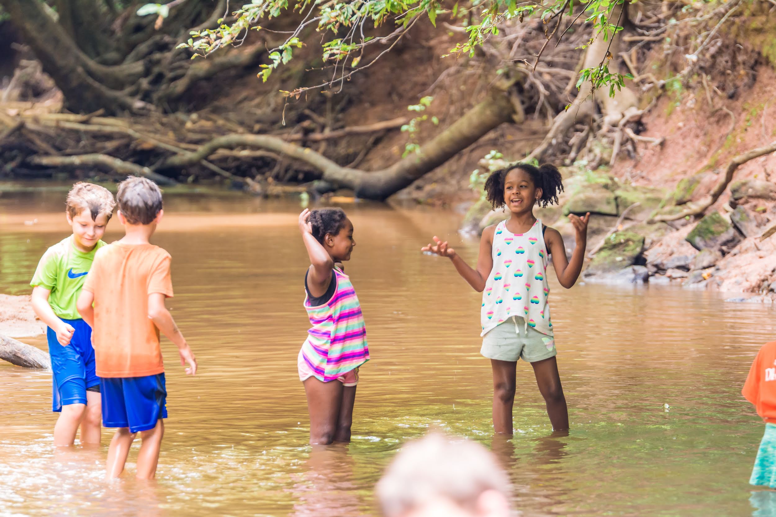 alt=Photo of children standing and talking in Lake Haigler at the Anne Springs Close Greenway