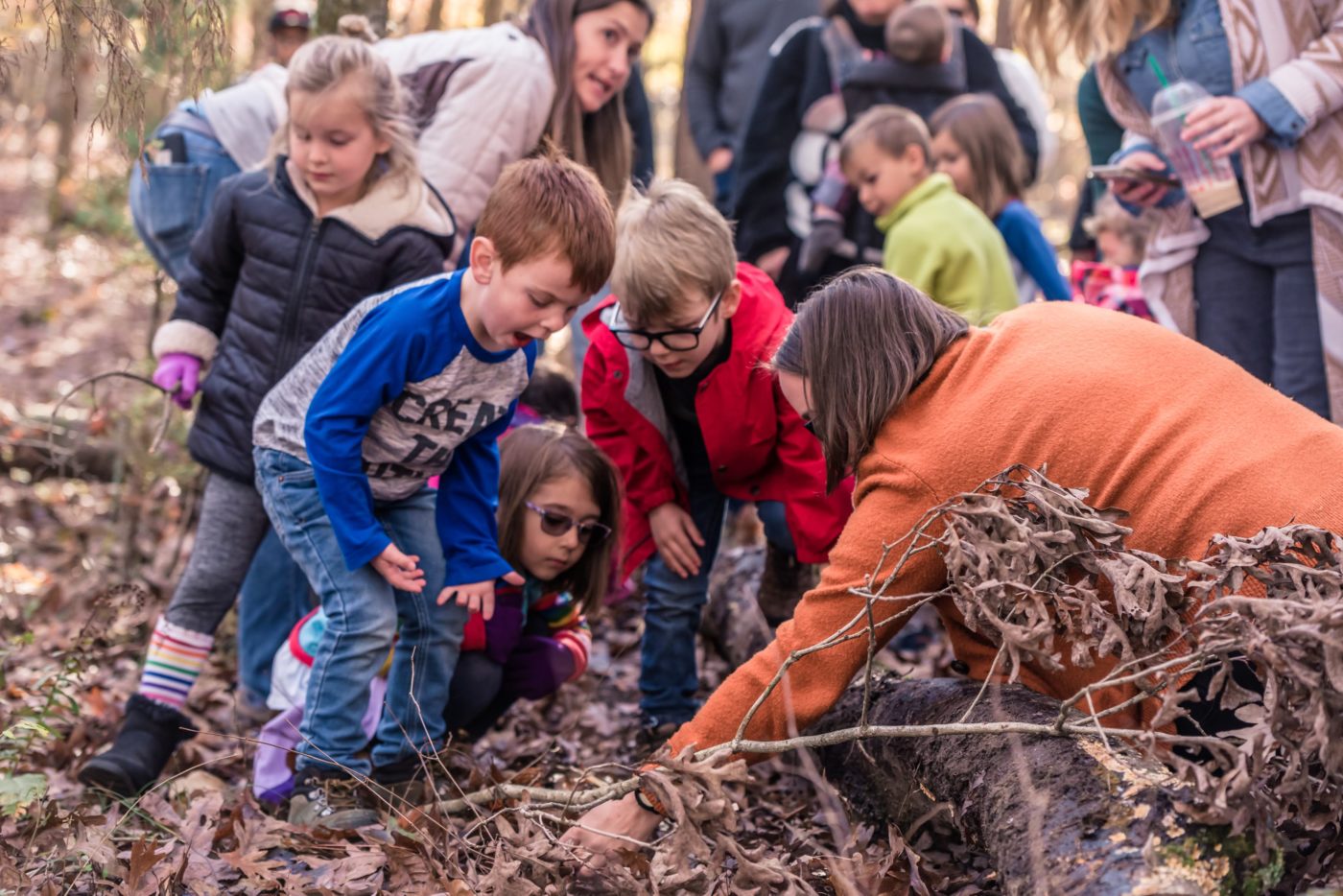 alt=Photo of children gathered around looking at the ground at the Anne Springs Close Greenway