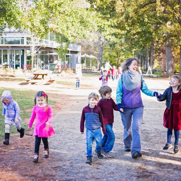alt=Photo of preschool teacher holding hands with students at the Gateway