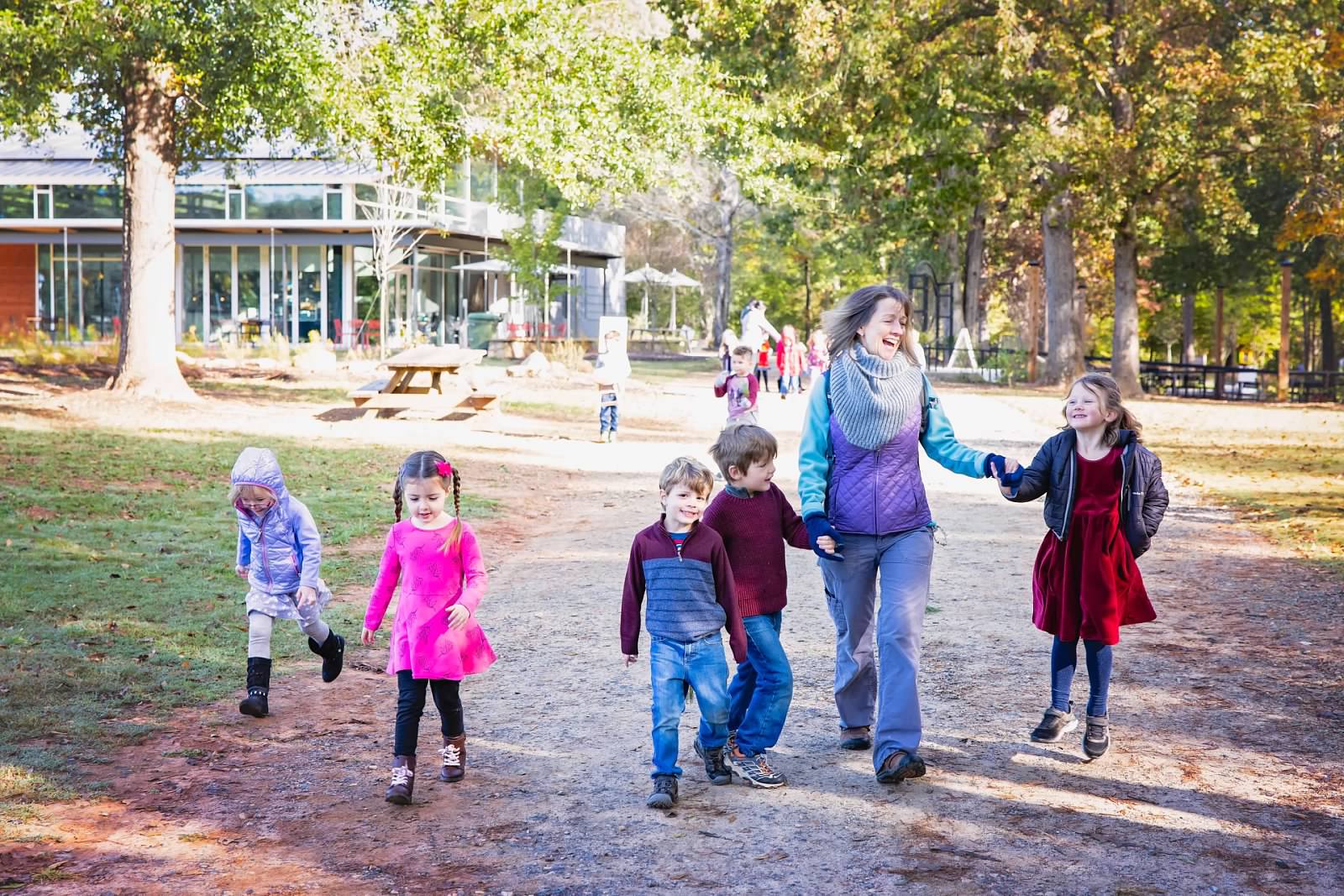 alt=Photo of preschool teacher holding hands with students at the Gateway
