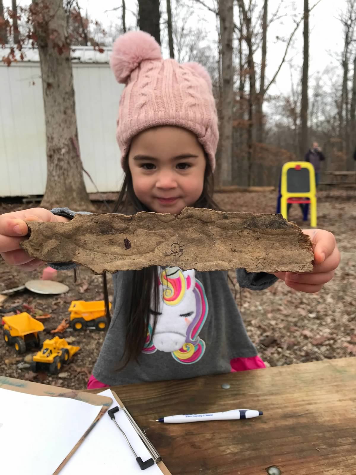 alt=Photo of young girl holding a piece of bark at the Anne Springs Close Greenway