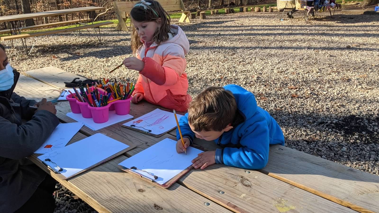 alt=Photo of children coloring outdoors at the Anne Springs Close Greenway