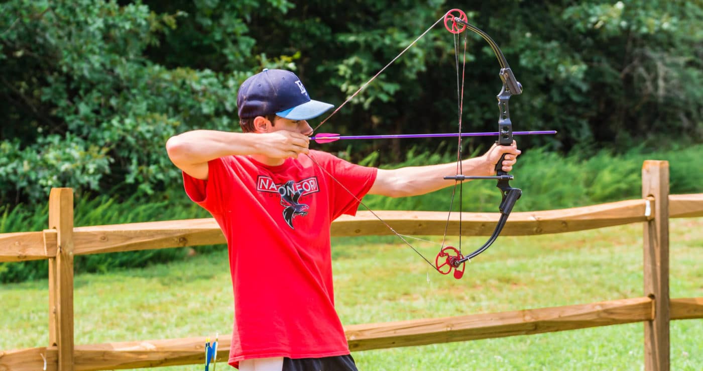 alt=Photo of teen boy practicing archery at the Anne Springs Close Greenway