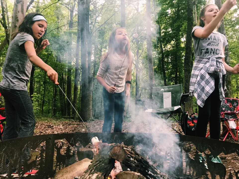 alt=Photo of 3 young girls roasting marshmallows at the Anne Springs Close Greenway