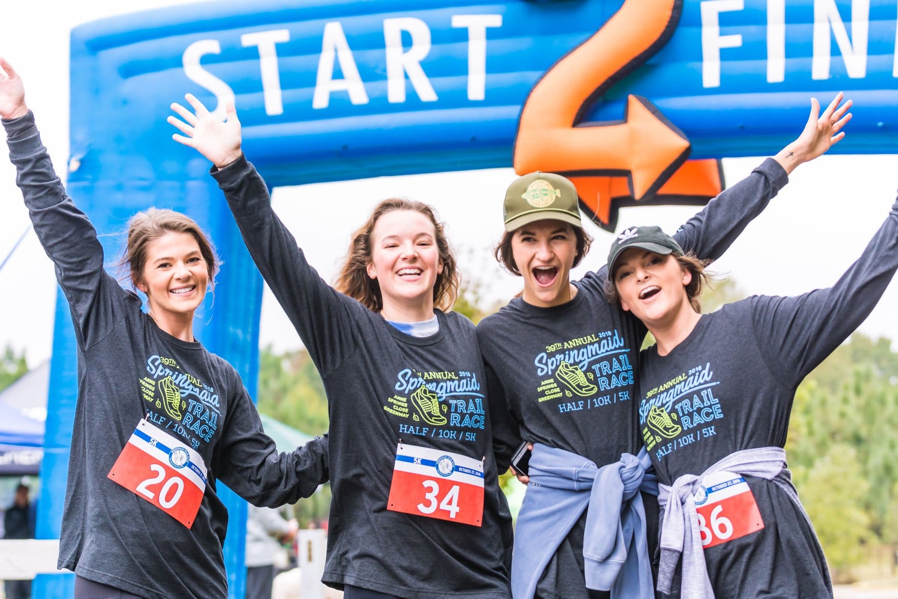 Photo of 4 female runners posing at the finish line of the Springmaid Trail Race at Springmaid Mountain