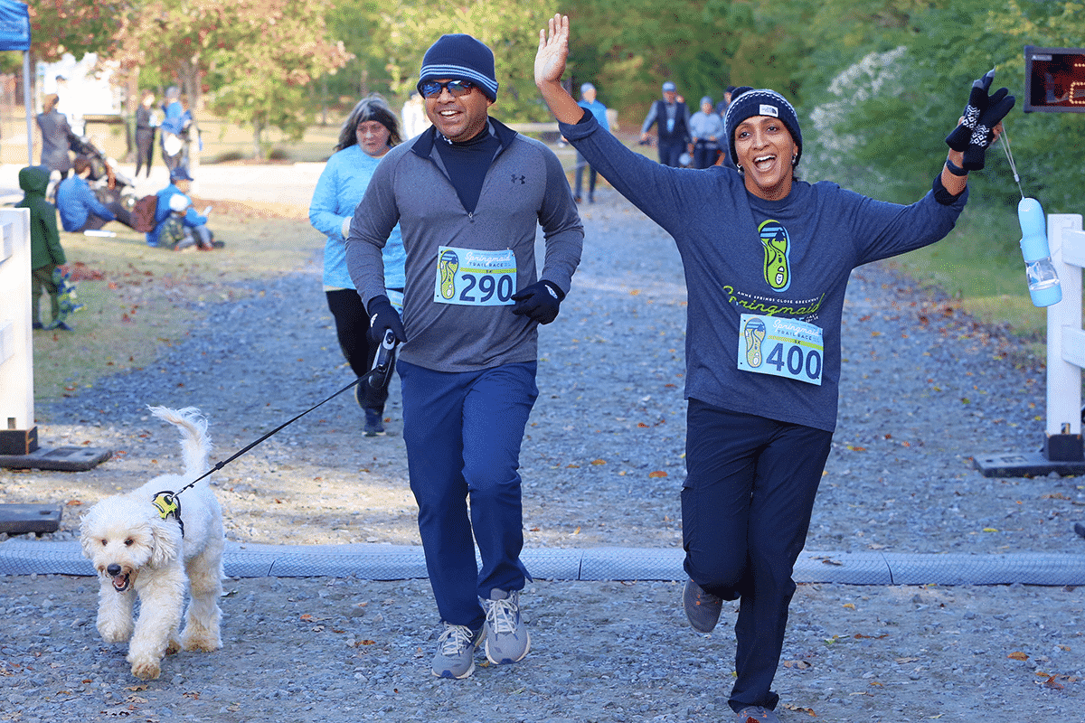 alt=Photo of a couple crossing the finish line of the Springmaid Trail Race