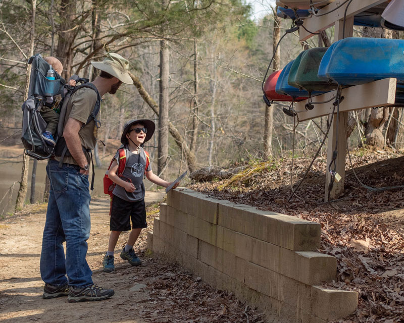 Photo of a father and son looking at the kayaks near the Archers Loop Trail at the Anne Springs Close Greenway