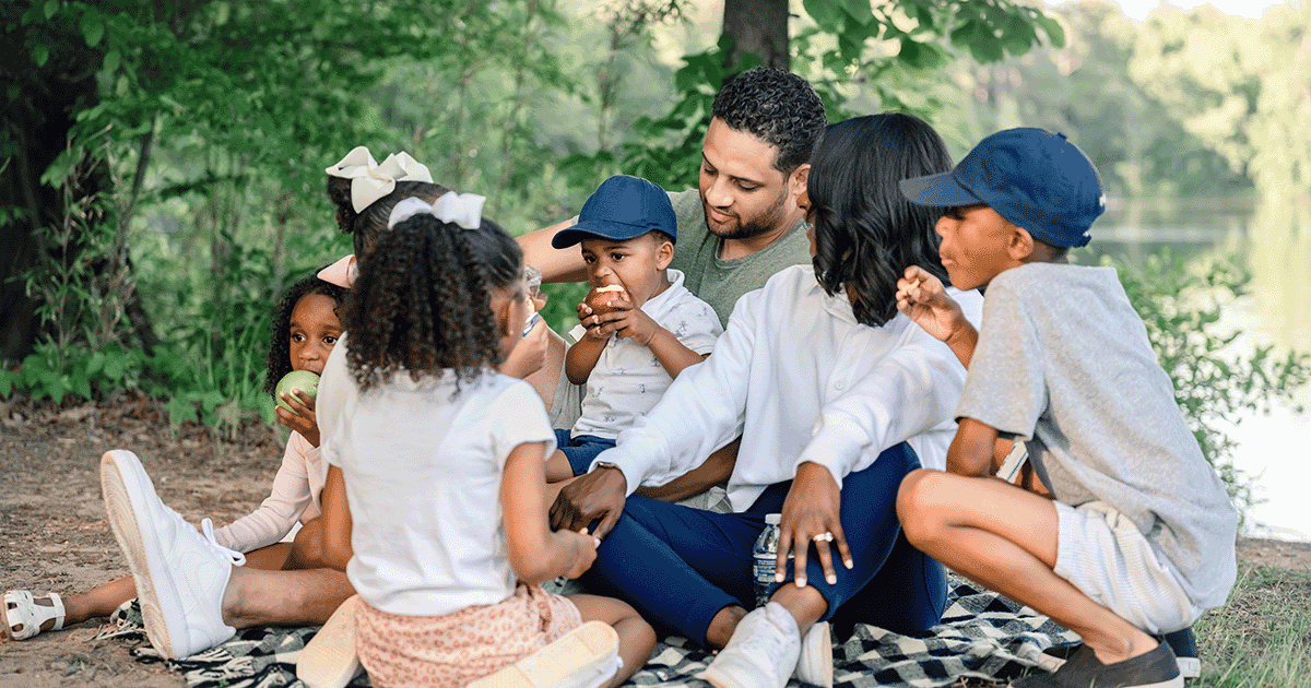 Photo of a mother and father and their 5 children enjoying a family picnic at the Anne Springs Close Greenway