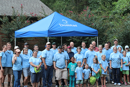 Photo of Domtar employees and family members posing for the camera in front of a Domtar tent