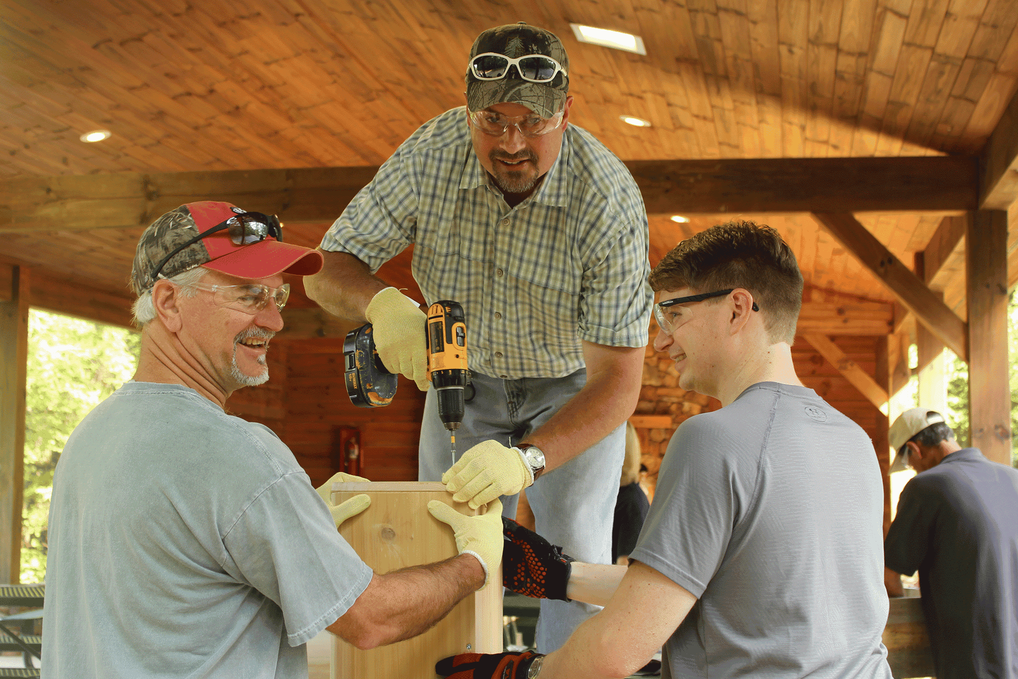 Photo of 3 men drilling nails into a birdhouse