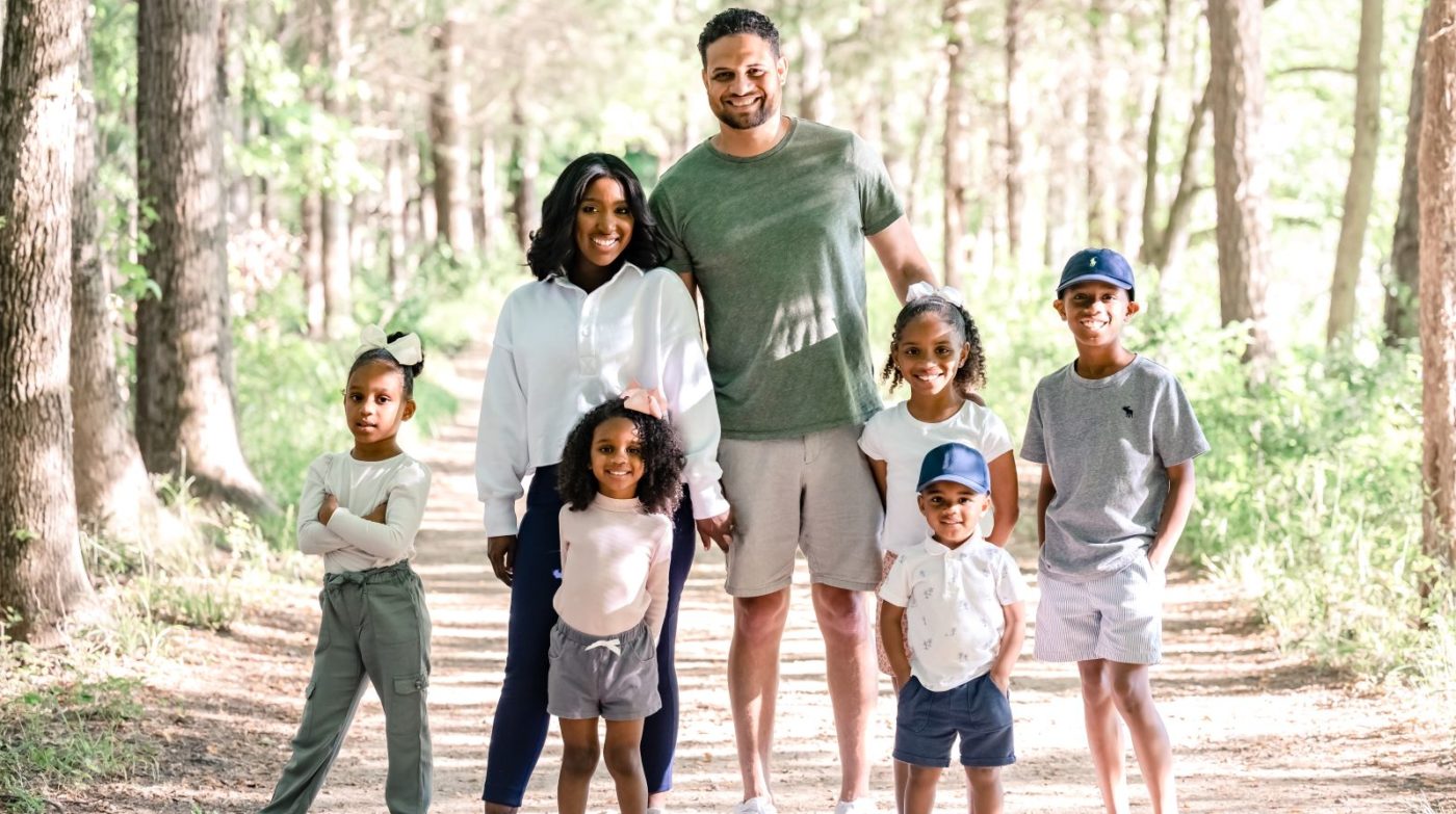 Mother and father smiling together with their 5 children standing in front at the land dam on Haigler Loop