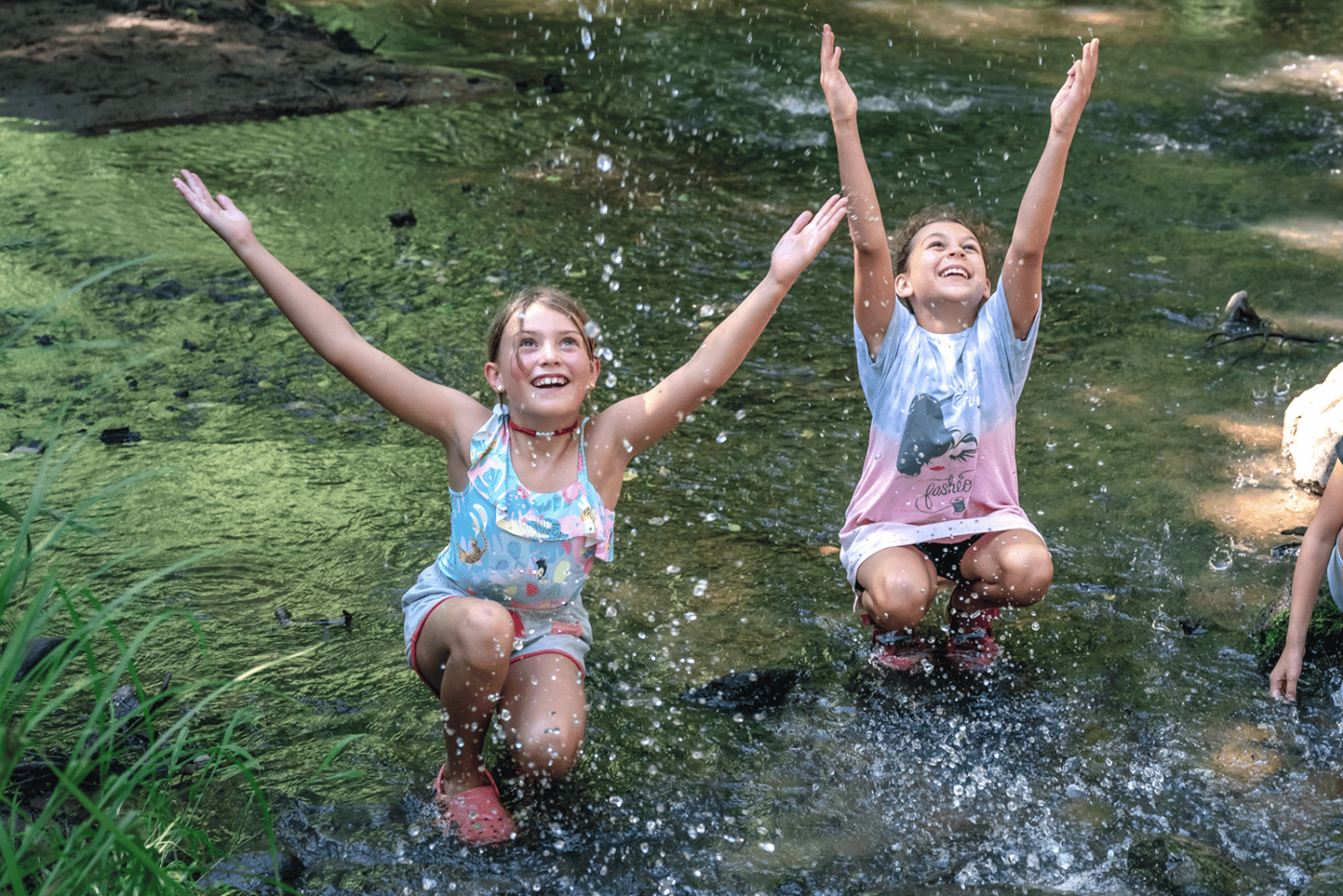 alt=Photo of 2 young girls splashing water in Steele Creek at the Anne Springs Close Greenway