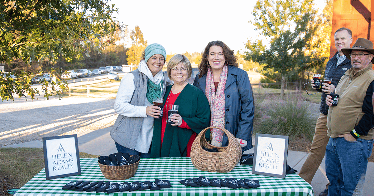Photo of Helen Adams Realty Fort Mill employees standing at the company's corporate table at an Anne Springs Close Greenway event