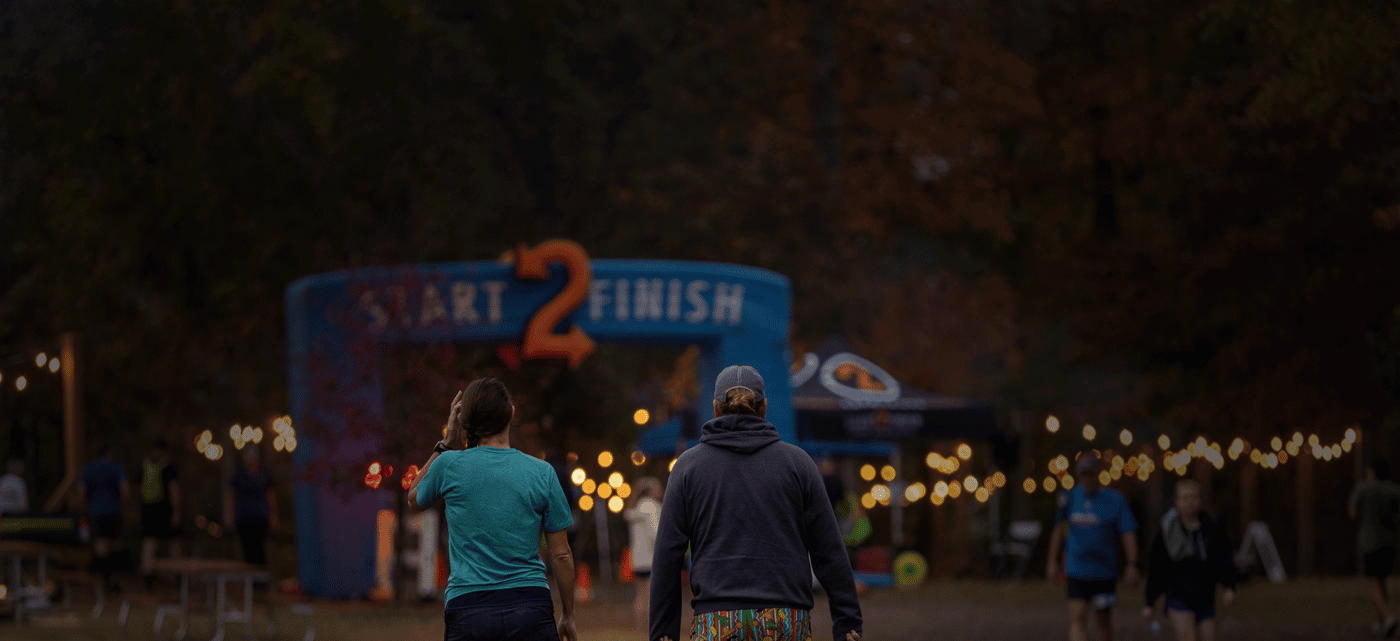 alt=Couple walking towards the starting point of the Night Owl 5K at the Anne Springs Close Greenway