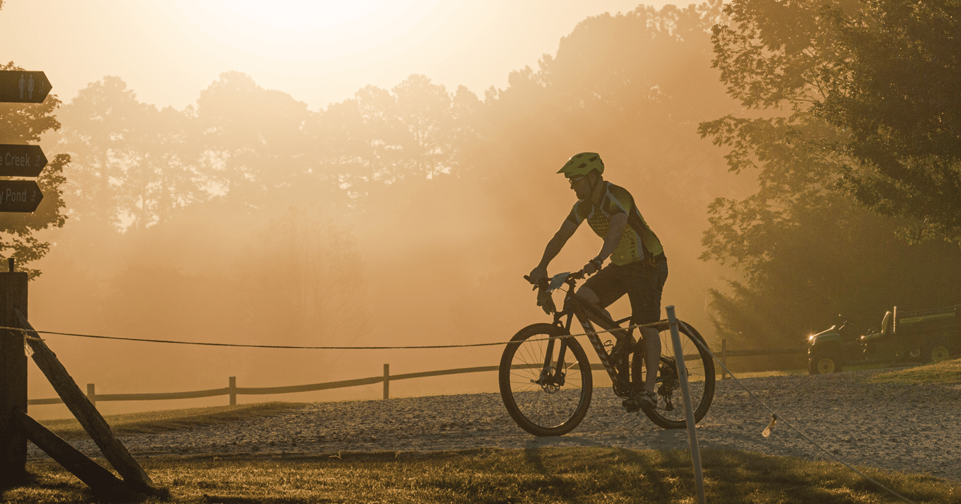 alt=Cycler biking through a trail at the Treeshaker Mountain Bike Challenge Race