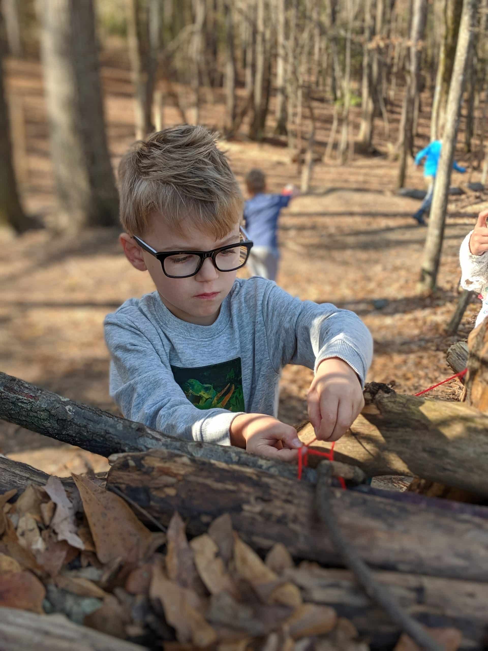 Photo of young boy building a fort with wood and zip ties at the Anne Springs Close Greenway