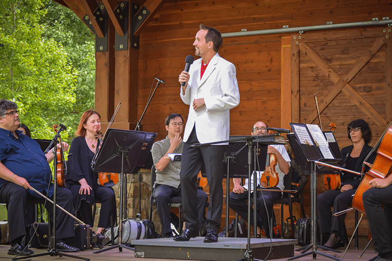 conductor of Charlotte Symphony Orchestra addresses the crowd at Anne Springs Close Greenway's amphitheater stage