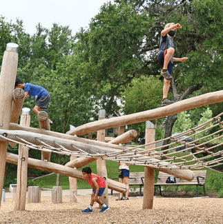 Children playing on the climbing structure at the Schroering Forest Playground at Anne Springs Close Greenway