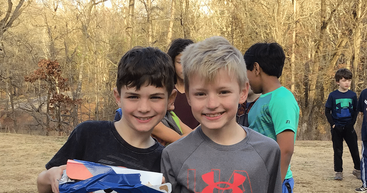 two boys smile for a photo outside