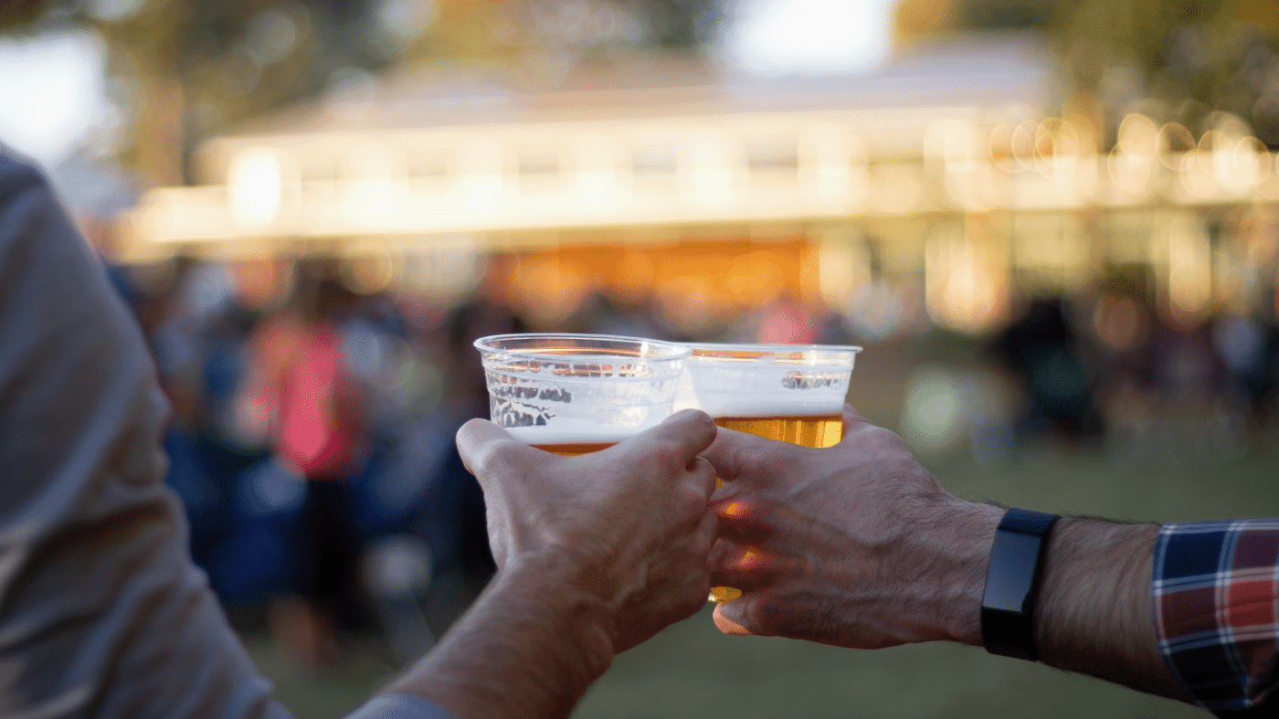 Image shows two men toasting two draft beers outside at the Anne Springs Close Greenway