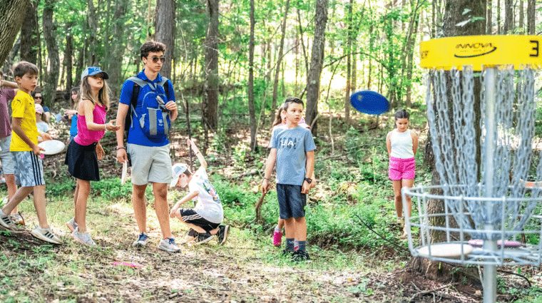 Summer camper throws a disc at Anne Springs Close Greenway's disc golf course