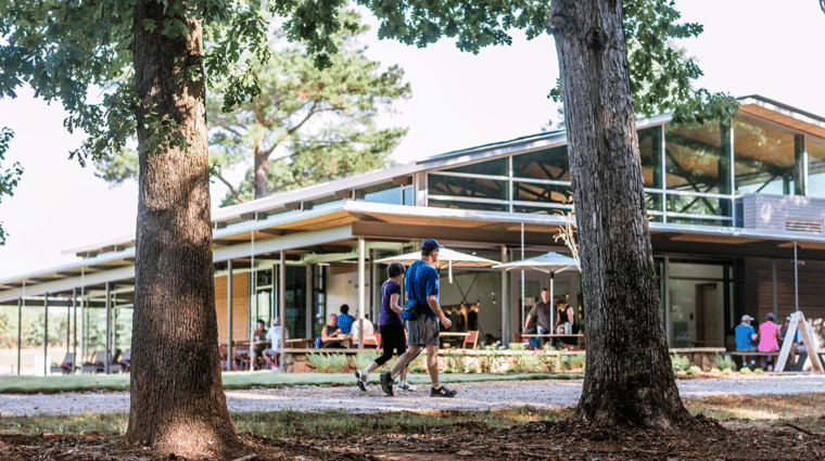 Couple walks on gravel trail at the Anne Springs Close Greenway outside of the Greenway's on-site restaurant on visitor center.