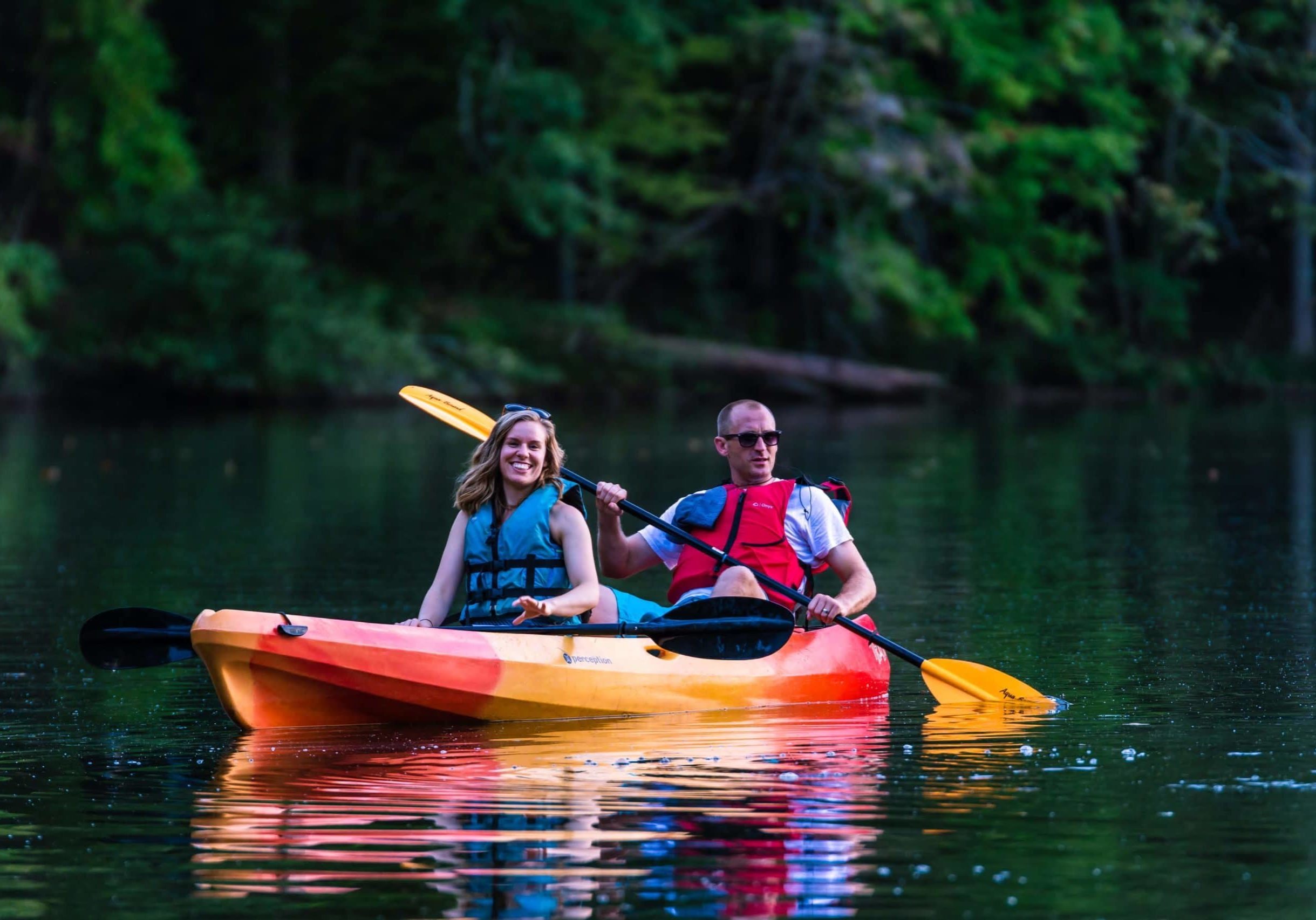 alt=Photo of couple smiling while kayaking on Lake Haigler at the Anne Springs Close Greenway