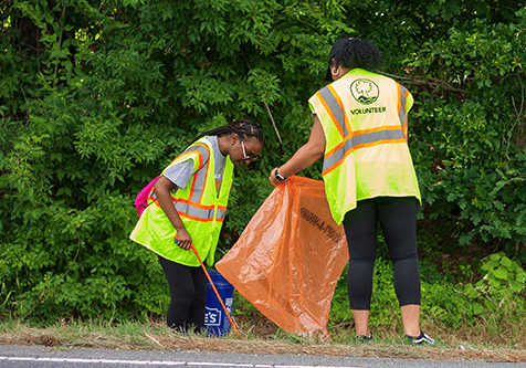 Photo of 2 women participating in litter clean up on the side of the Anne Springs Close Greenway