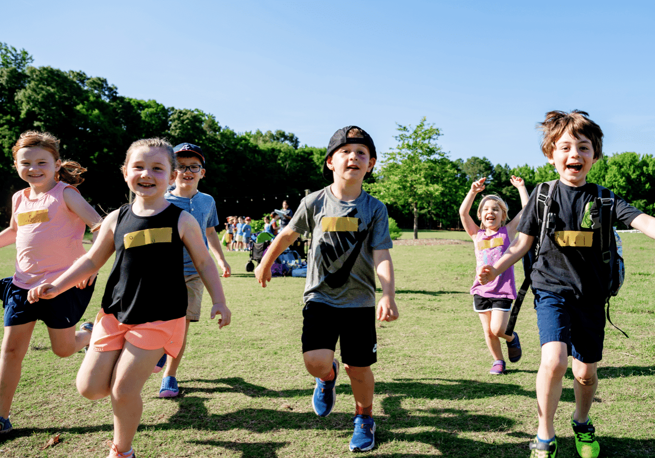 Excited campers running through a field during an outdoor activity at Anne Springs Close Greenway Summer Camp.