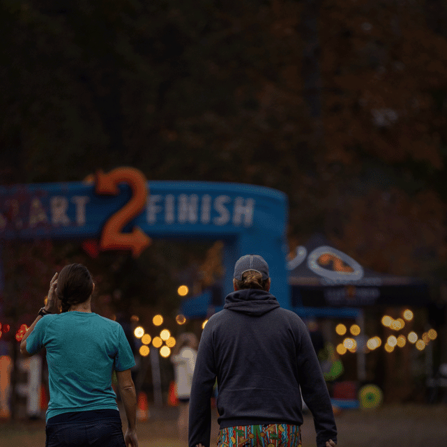 alt=Couple walking towards the starting point of the Night Owl 5K at the Anne Springs Close Greenway